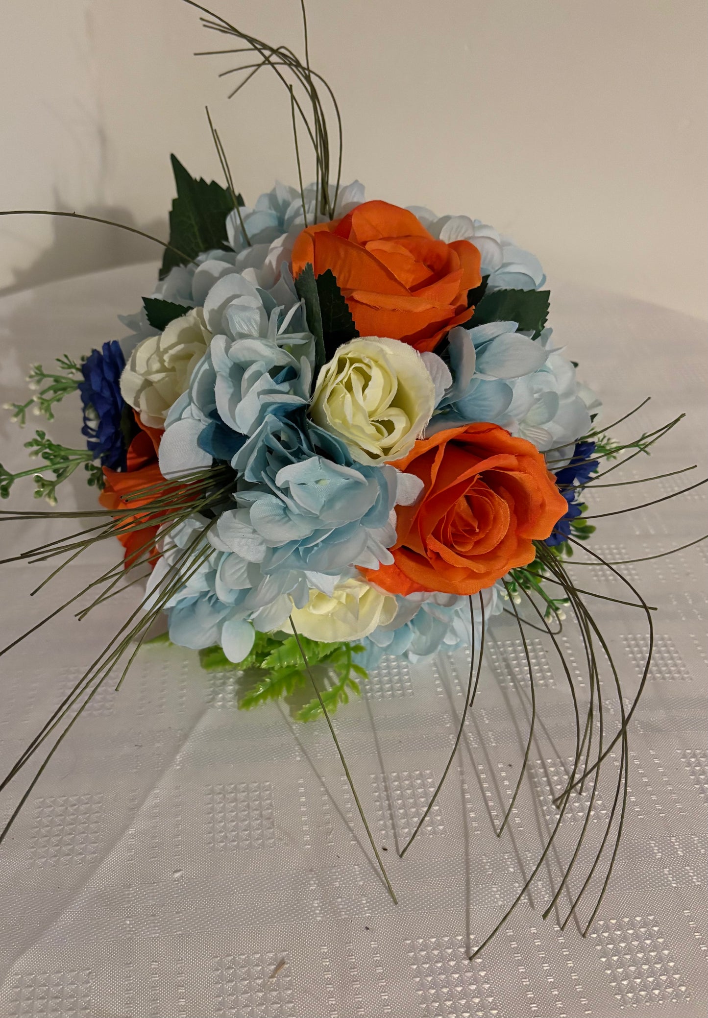 Bridal bouquet of blue and orange with mixed grasses.