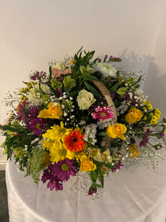 Pinks, yellows, mauves and white flowers arranged in a basket