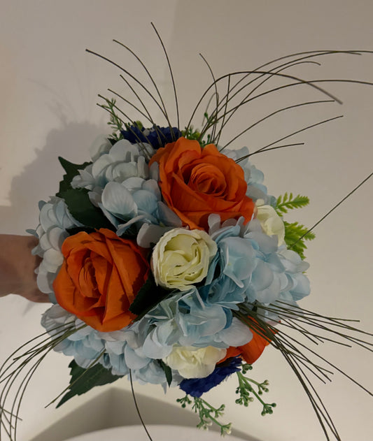 Posy bouquet of orange open roses and blue hydrangeas and grasses