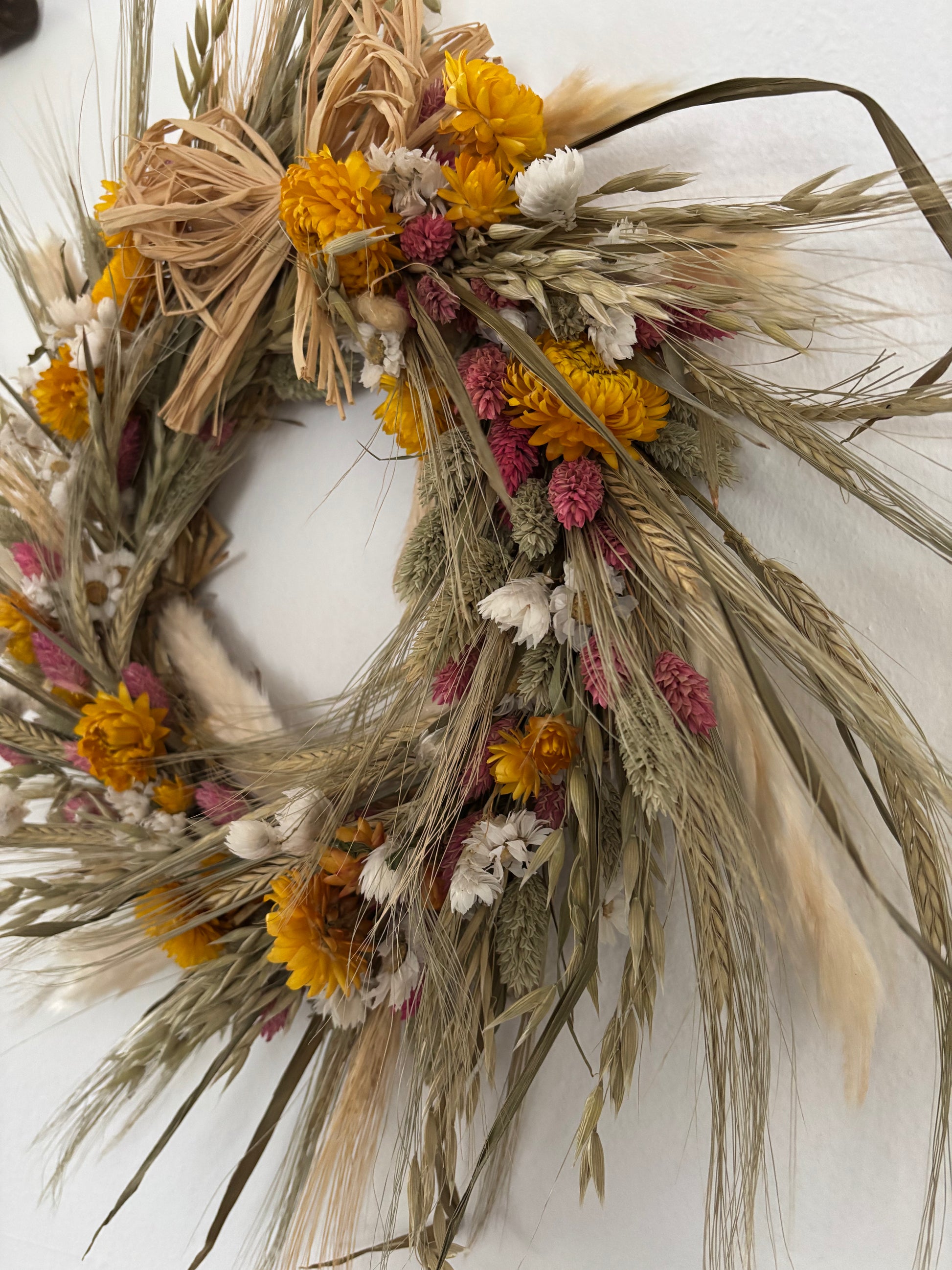 Dried flower wreath, yellow, ivory, white, pink and green. Side view