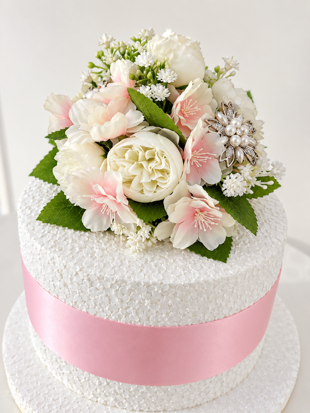 Close up image of pale pink and cream cake topper with pretty diamante.