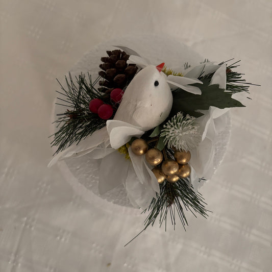 Decorative cake flower arrangement with a white dove, pine cones, and berries.