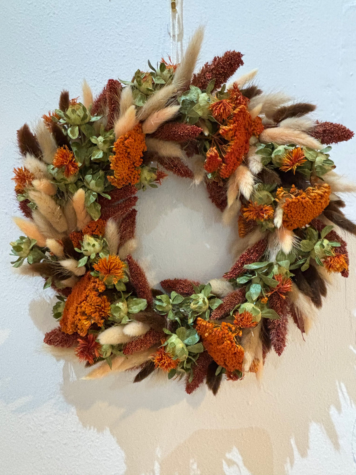 Wreath of orange achillea, mixed laguras grass and red millets.