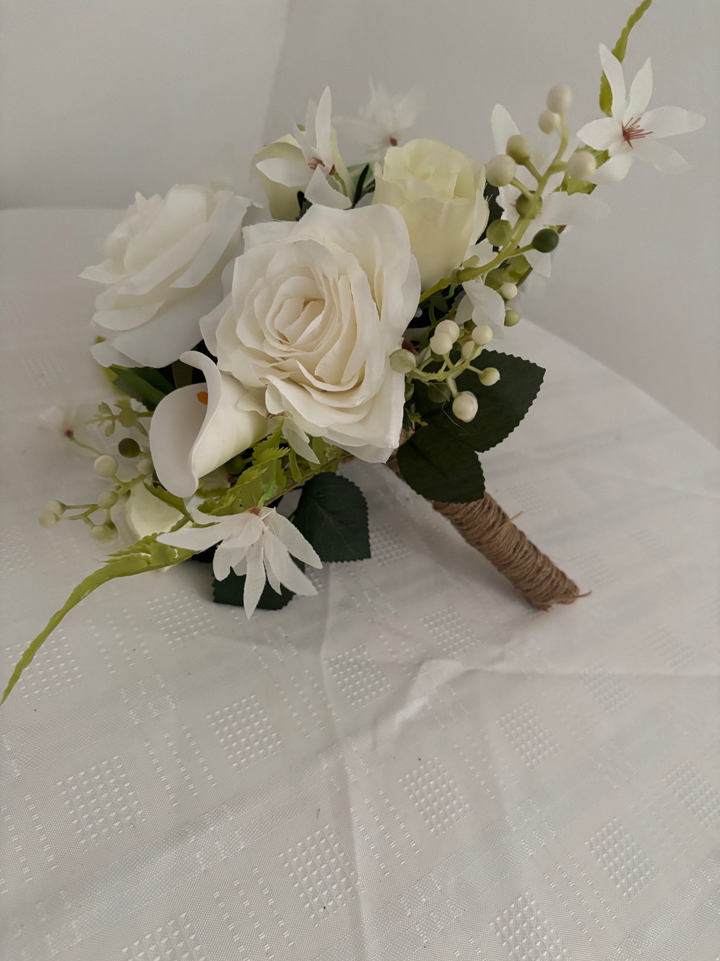 Silk artificial bridal shower bouquet of pale ivory rose buds, white open garden roses and lilies surrounded by blossoms, mixed greenery with eucalyptus.