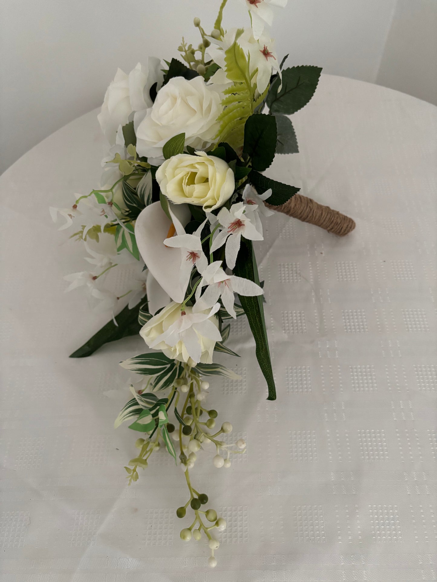 Silk artificial bridal shower bouquet of pale ivory rose buds, white open garden roses and lilies surrounded by blossoms, mixed greenery with eucalyptus.