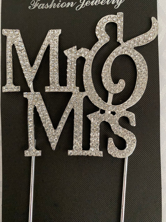 A diamante cake topper featuring the text 'Mr & Mrs' set with sparkling clear embellishments.