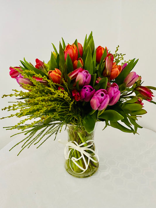 Glass vase filled with mixed coloured tulips