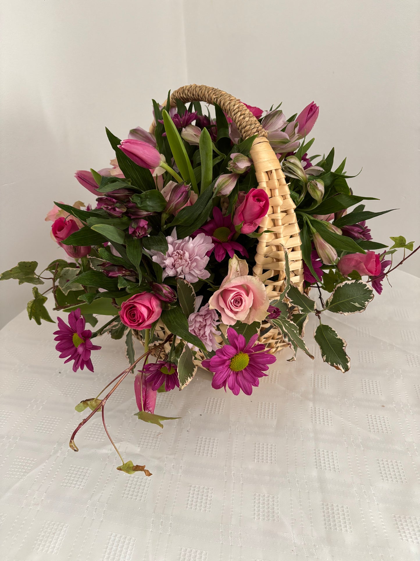 Fresh flowers in shades of pink arranged in a wicker basket